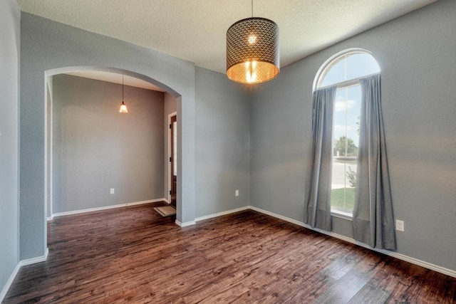 125 Lillian Dr, Taylor, TX 76574 - unfurnished room with arched walkways, plenty of natural light, wood finished floors, and a textured ceiling