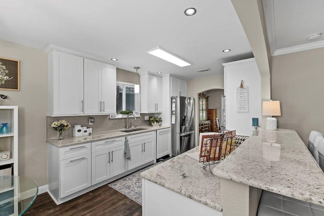 12403 Cassady Dr, Austin, TX 78727 - kitchen featuring stainless steel fridge, arched walkways, dishwasher, tasteful backsplash, and a peninsula