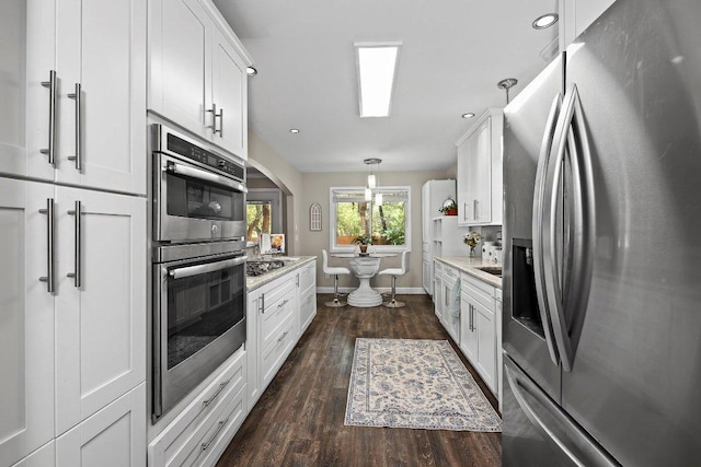 12403 Cassady Dr, Austin, TX 78727 - kitchen with appliances with stainless steel finishes, white cabinetry, dark wood finished floors, recessed lighting, and hanging light fixtures