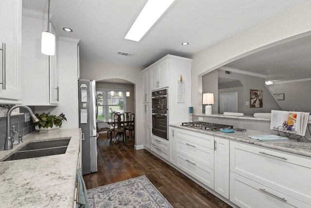 12403 Cassady Dr, Austin, TX 78727 - kitchen with stainless steel appliances, arched walkways, white cabinetry, dark wood-style floors, and recessed lighting