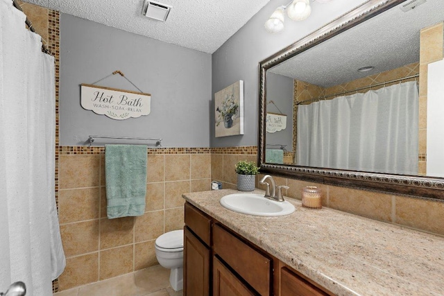 12403 Cassady Dr, Austin, TX 78727 - bathroom with a textured ceiling, vanity, tile patterned flooring, tile walls, and a wainscoted wall