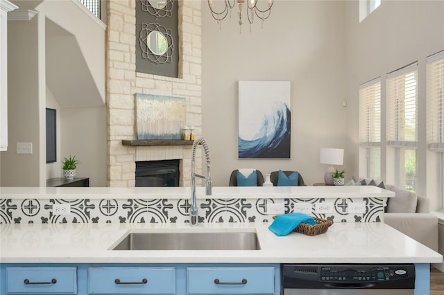 21 Green Terrace Cv, Lakeway, TX 78734 - kitchen featuring blue cabinets, open floor plan, dishwasher, a high ceiling, and a stone fireplace