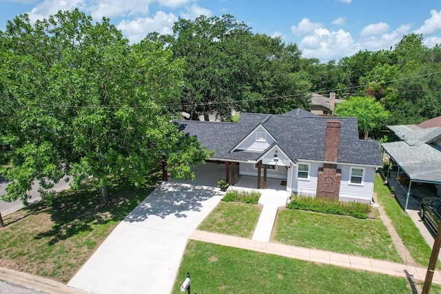 522 S Walnut Ave, Luling, TX 78648 - view of front of home with concrete driveway, a front yard, roof with shingles, and a chimney