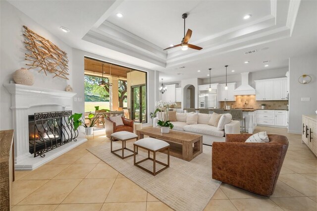 107 Bella Strada Cv, Lakeway, TX 78734 - living area with a tray ceiling, ceiling fan, light tile patterned floors, a warm lit fireplace, and recessed lighting