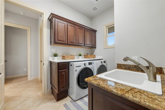 107 Bella Strada Cv, Lakeway, TX 78734 - laundry area featuring washing machine and dryer, cabinet space, and light tile patterned floors
