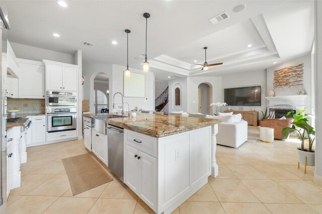 107 Bella Strada Cv, Lakeway, TX 78734 - kitchen with stainless steel appliances, arched walkways, a ceiling fan, tasteful backsplash, and light tile patterned floors