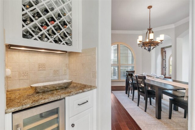 107 Bella Strada Cv, Lakeway, TX 78734 - indoor dry bar with beverage cooler, crown molding, dark wood-style flooring, a chandelier, and backsplash