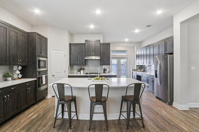 113 Berkeley Pl, Georgetown, TX 78628 - kitchen with appliances with stainless steel finishes, decorative backsplash, a breakfast bar area, an island with sink, and recessed lighting