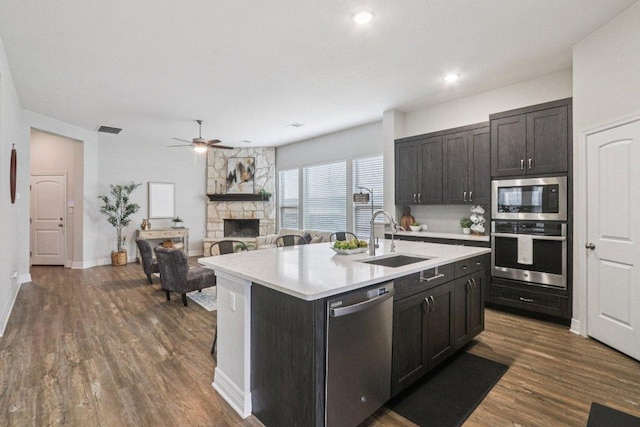 113 Berkeley Pl, Georgetown, TX 78628 - kitchen featuring appliances with stainless steel finishes, light countertops, ceiling fan, a stone fireplace, and recessed lighting