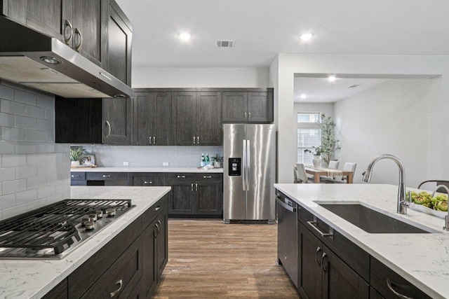 113 Berkeley Pl, Georgetown, TX 78628 - kitchen featuring appliances with stainless steel finishes, exhaust hood, light wood-style floors, decorative backsplash, and recessed lighting