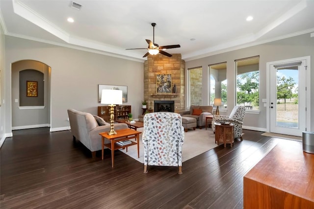 106 Packsaddle Dr, Bastrop, TX 78602 - living room featuring ceiling fan, a stone fireplace, dark wood-style flooring, crown molding, and arched walkways