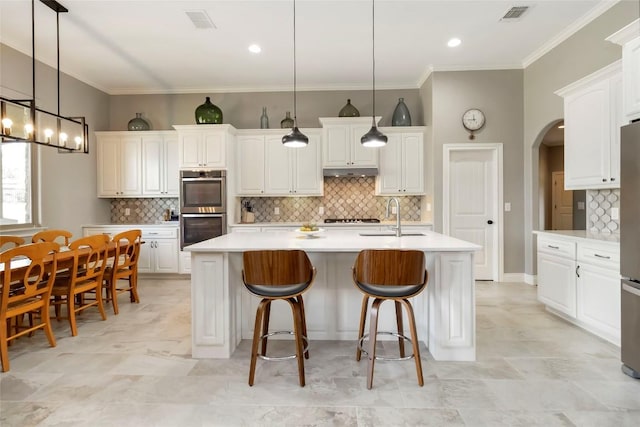 106 Packsaddle Dr, Bastrop, TX 78602 - kitchen with appliances with stainless steel finishes, arched walkways, decorative backsplash, white cabinetry, and crown molding