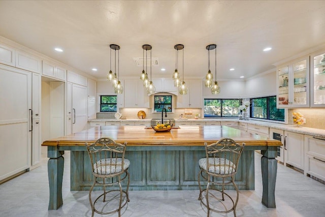 14305 Geronimo St, Leander, TX 78641 - kitchen with decorative backsplash, white cabinets, glass insert cabinets, a large island, and pendant lighting