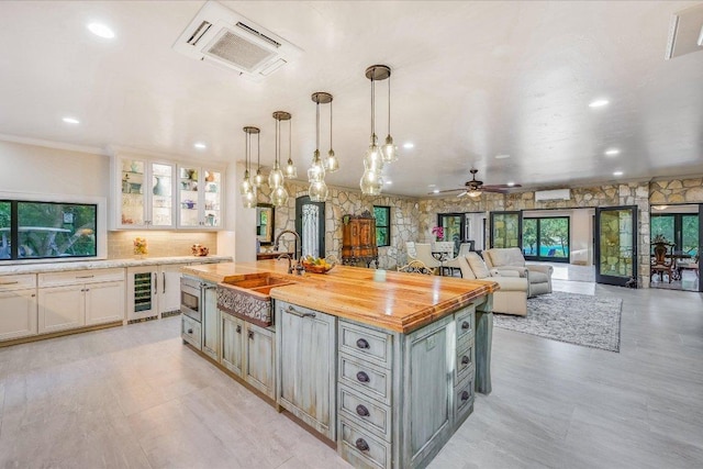 14305 Geronimo St, Leander, TX 78641 - kitchen with wine cooler, an island with sink, ceiling fan, glass insert cabinets, and decorative light fixtures