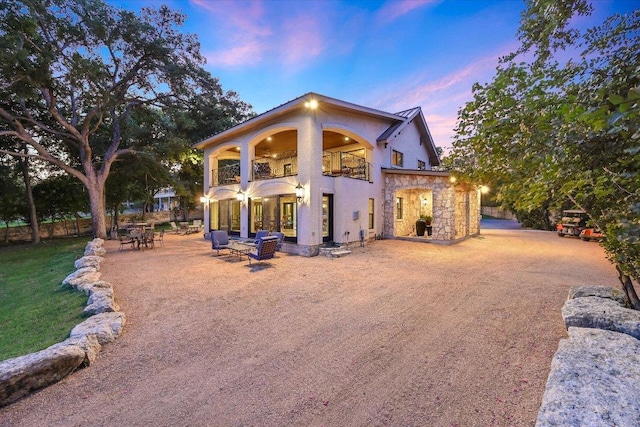 14305 Geronimo St, Leander, TX 78641 - back of property at dusk with a balcony, stucco siding, a patio, and stone siding