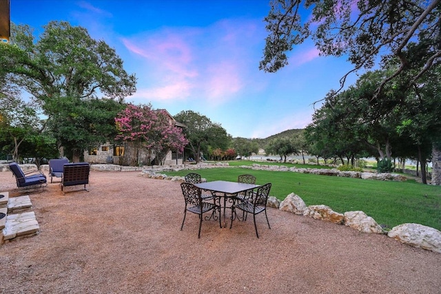 14305 Geronimo St, Leander, TX 78641 - patio terrace at dusk featuring a yard, a patio, and outdoor dining space