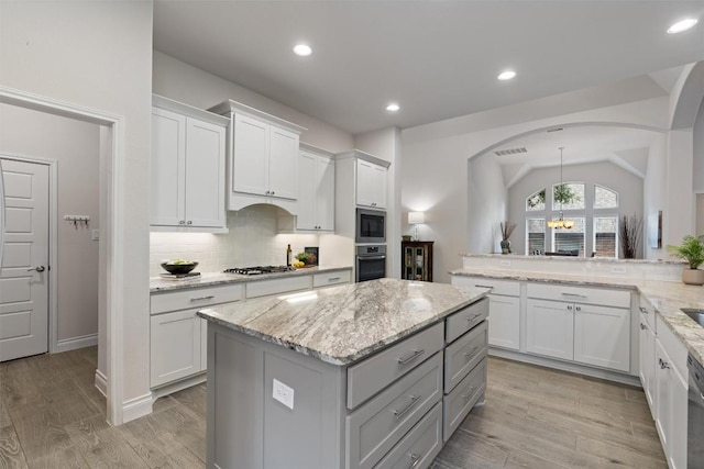 624 Judge Fisk Dr, Leander, TX 78641 - kitchen featuring stainless steel appliances, decorative backsplash, a kitchen island, white cabinetry, and light stone counters