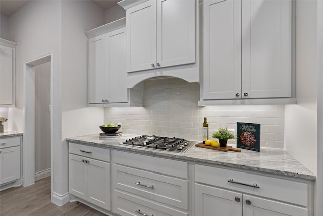 624 Judge Fisk Dr, Leander, TX 78641 - kitchen with stainless steel gas stovetop, wood finished floors, white cabinetry, decorative backsplash, and light stone countertops