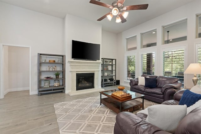 624 Judge Fisk Dr, Leander, TX 78641 - living room featuring a ceiling fan, light wood finished floors, a towering ceiling, and a glass covered fireplace