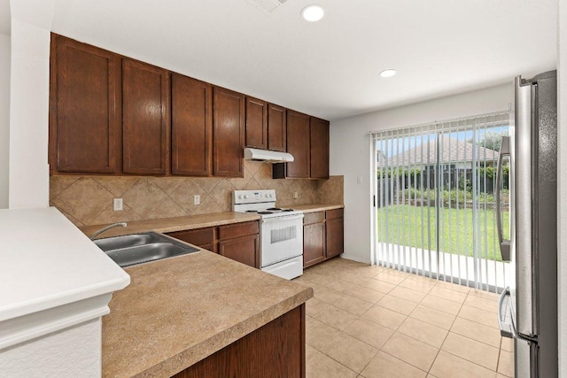 324 Kingfisher Ln, Leander, TX 78641 - kitchen with white electric range oven, freestanding refrigerator, backsplash, under cabinet range hood, and light countertops