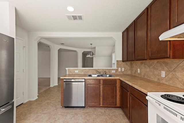 324 Kingfisher Ln, Leander, TX 78641 - kitchen featuring appliances with stainless steel finishes, backsplash, light countertops, a peninsula, and arched walkways