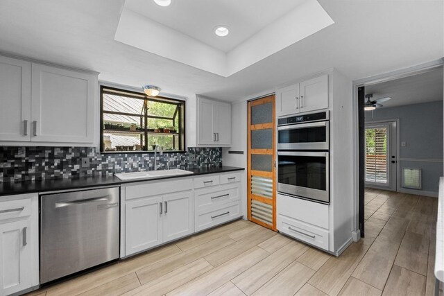 6110 Gardenridge Holw, Austin, TX 78750 - kitchen with appliances with stainless steel finishes, dark countertops, backsplash, a raised ceiling, and white cabinets