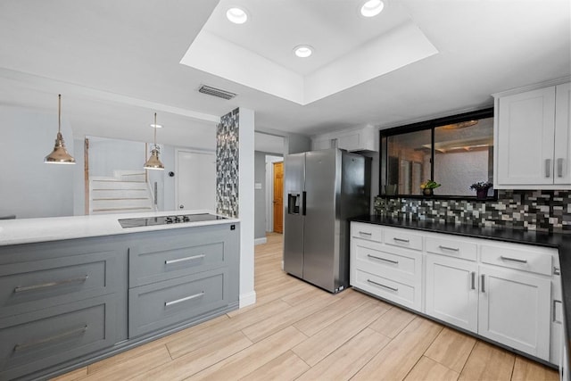 6110 Gardenridge Holw, Austin, TX 78750 - kitchen with stainless steel fridge, black electric stovetop, decorative backsplash, a raised ceiling, and light wood finished floors