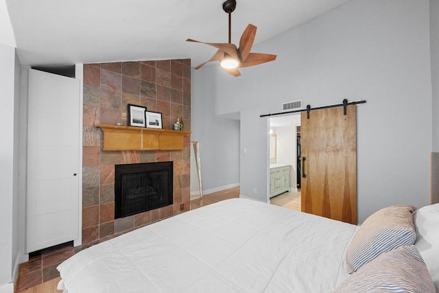 6110 Gardenridge Holw, Austin, TX 78750 - bedroom with a barn door, a tile fireplace, high vaulted ceiling, ensuite bathroom, and a ceiling fan