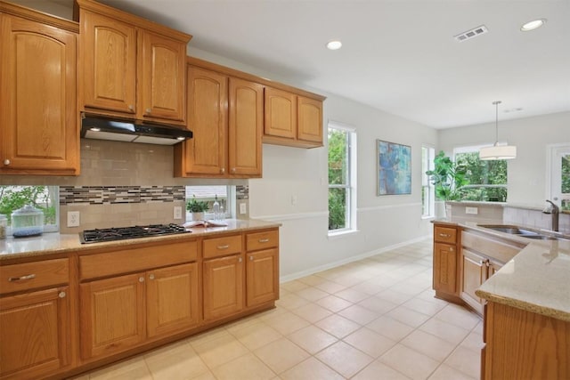 6520 Walebridge Ln, Austin, TX 78739 - kitchen with gas cooktop, under cabinet range hood, backsplash, light stone counters, and decorative light fixtures