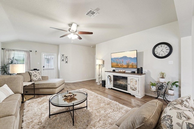 184 Pivot Dr, Taylor, TX 76574 - living area with ceiling fan, wood finished floors, vaulted ceiling, and a glass covered fireplace