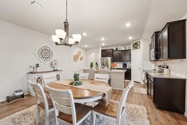 184 Pivot Dr, Taylor, TX 76574 - dining area with arched walkways, light wood-style flooring, a chandelier, and recessed lighting