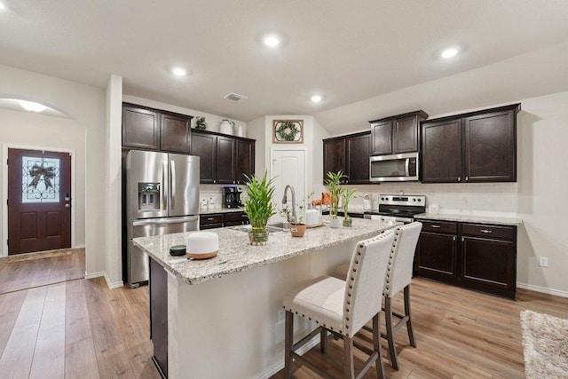 184 Pivot Dr, Taylor, TX 76574 - kitchen with stainless steel appliances, tasteful backsplash, light wood-style floors, a kitchen breakfast bar, and recessed lighting