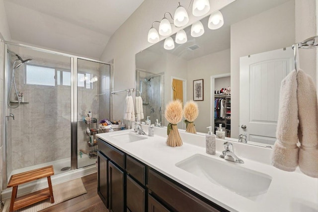 184 Pivot Dr, Taylor, TX 76574 - bathroom featuring a stall shower, double vanity, a walk in closet, lofted ceiling, and wood finished floors