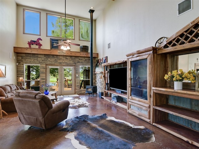 762 Karisch Rd, Giddings, TX 78942 - living room with a wood stove, a high ceiling, concrete flooring, a ceiling fan, and french doors