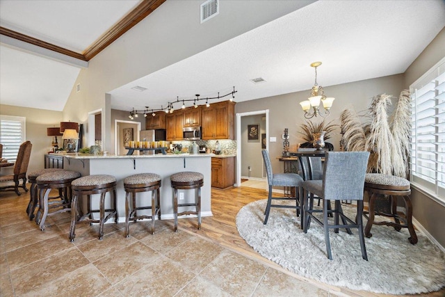 515 Wesley Ridge Dr, Spicewood, TX 78669 - kitchen featuring brown cabinets, appliances with stainless steel finishes, a chandelier, rail lighting, and plenty of natural light