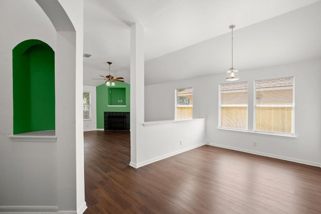 14608 Menifee St, Austin, TX 78725 - unfurnished room featuring a ceiling fan, dark wood-style flooring, vaulted ceiling, a tiled fireplace, and arched walkways