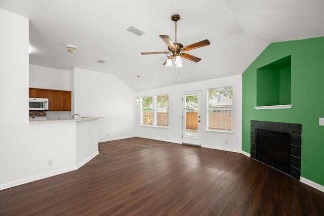 14608 Menifee St, Austin, TX 78725 - unfurnished living room with vaulted ceiling, dark wood-style flooring, ceiling fan, and a tile fireplace