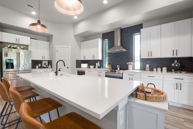 809 John Price, Blanco, TX 78606 - kitchen featuring wall chimney exhaust hood, stainless steel appliances, a breakfast bar area, backsplash, and a center island with sink