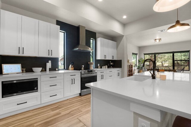 809 John Price, Blanco, TX 78606 - kitchen with wall chimney range hood, appliances with stainless steel finishes, light countertops, decorative backsplash, and recessed lighting
