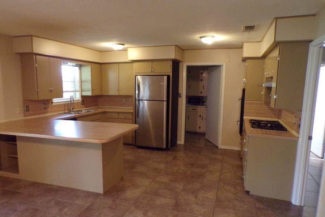 729 Yegua Dr, Lexington, TX 78947 - kitchen with freestanding refrigerator, a peninsula, under cabinet range hood, tasteful backsplash, and gas stovetop