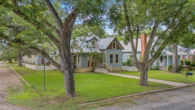 710 Gresham St, Smithville, TX 78957 - view of front of home with a chimney, a porch, a front lawn, and a metal roof