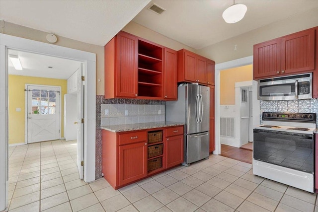 710 Gresham St, Smithville, TX 78957 - kitchen with appliances with stainless steel finishes, light tile patterned flooring, open shelves, and decorative backsplash