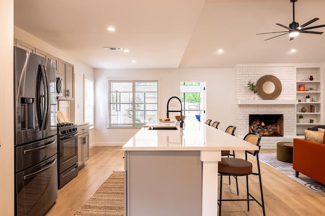 2306 Monarch Dr, Austin, TX 78748 - kitchen featuring appliances with stainless steel finishes, light wood-style floors, open floor plan, a kitchen island with sink, and a kitchen breakfast bar