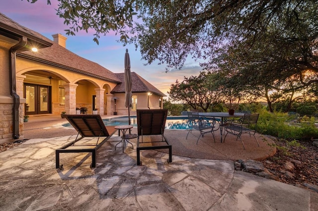 1006 Foothills Dr, Dripping Springs, TX 78620 - patio terrace at dusk featuring a patio area, an outdoor pool, and french doors