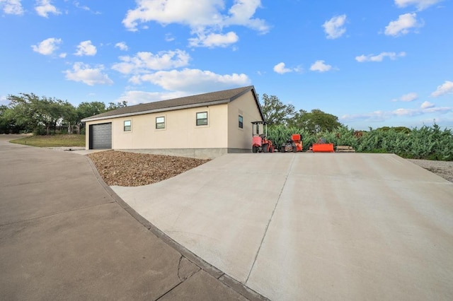 1006 Foothills Dr, Dripping Springs, TX 78620 - view of property exterior featuring concrete driveway, stucco siding, and an attached garage