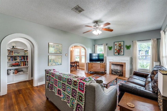 1106 S 11th St, Temple, TX 76504 - living area featuring arched walkways, ceiling fan, dark wood-style flooring, a textured ceiling, and a tiled fireplace