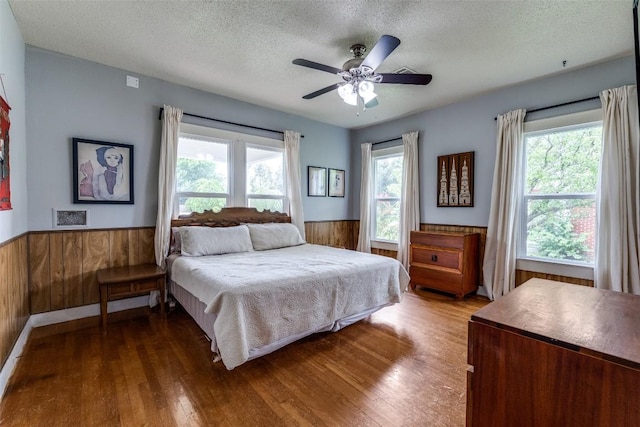 1106 S 11th St, Temple, TX 76504 - bedroom featuring wainscoting, wood walls, multiple windows, a textured ceiling, and wood finished floors
