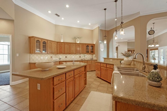1806 Carey Ave, Taylor, TX 76574 - kitchen featuring a spacious island, decorative backsplash, crown molding, glass insert cabinets, and light stone counters