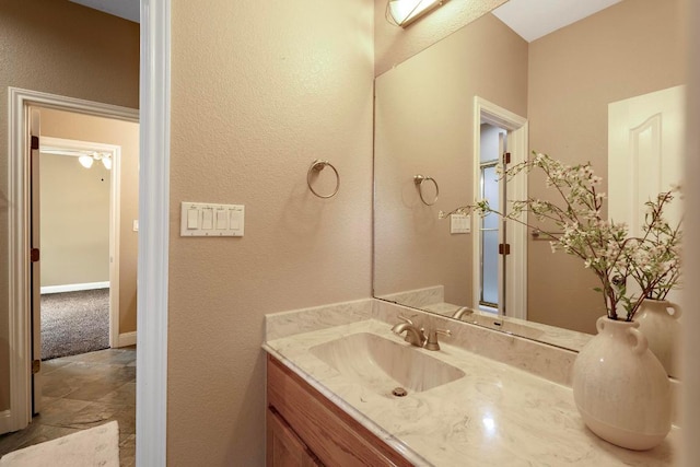 1806 Carey Ave, Taylor, TX 76574 - bathroom with vanity, a textured wall, and stone finish flooring