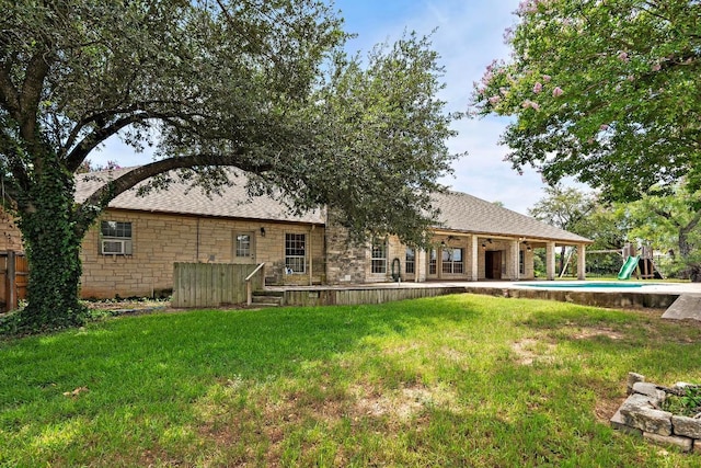 1806 Carey Ave, Taylor, TX 76574 - rear view of property with a yard, stone siding, a shingled roof, and a playground